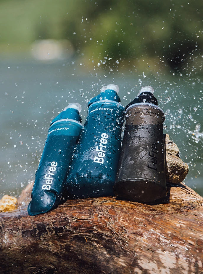 A lineup of Katadyn BeFree water filters featuring HydraPak’s flexible, collapsible flask design displayed in water splashes near a river.