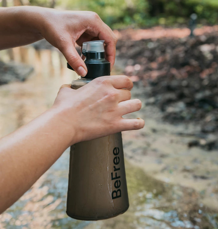 Close-up of a user opening a Katadyn BeFree filter system featuring HydraPak's soft, collapsible flask body to treat water outdoors.