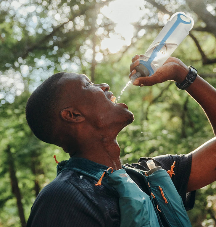 Close-up of a trail runner squeezing water into his mouth from an Osprey 500mL Soft Flask, clearly showcasing the internal WingStay™ Removable Flask Stabilizer.